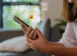 Concept per Come gestire la reputazione online: close up su mani di donna che tengono uno smartphone, da cui escono icone di recensioni positive
