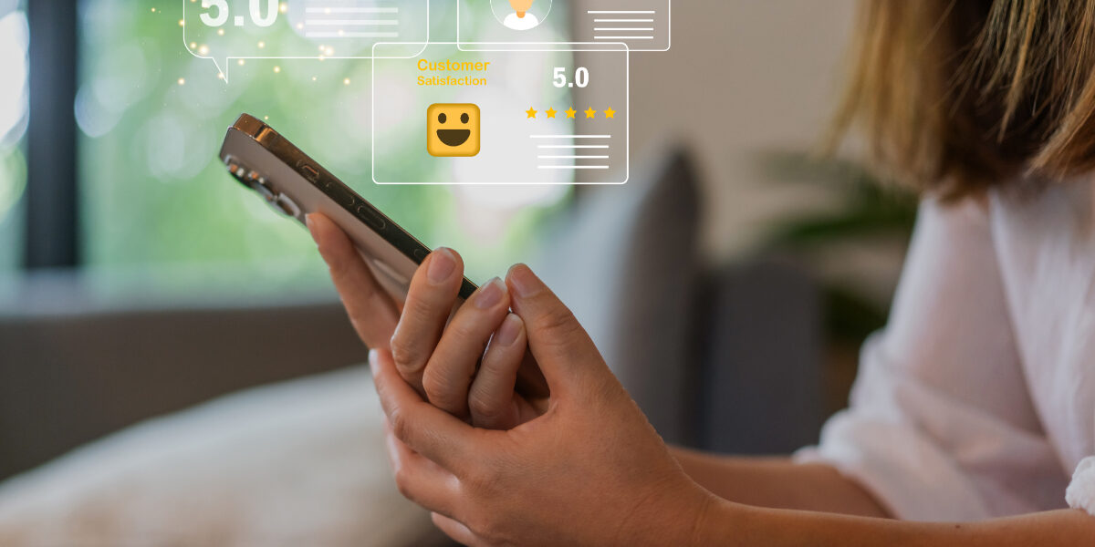Concept per Come gestire la reputazione online: close up su mani di donna che tengono uno smartphone, da cui escono icone di recensioni positive