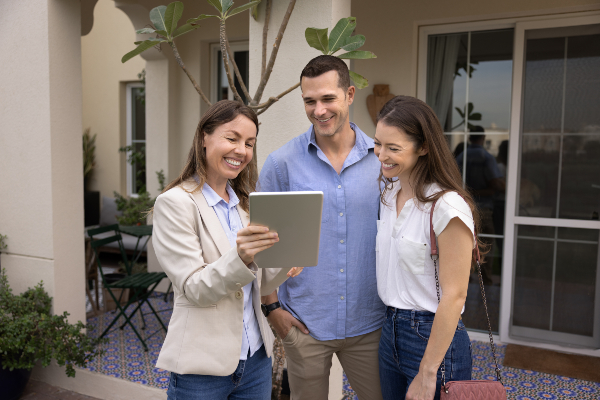 Concept per la gestione delle obiezioni nel settore immobiliare: consulente mostra rendering su di un tablet a una coppia di clienti